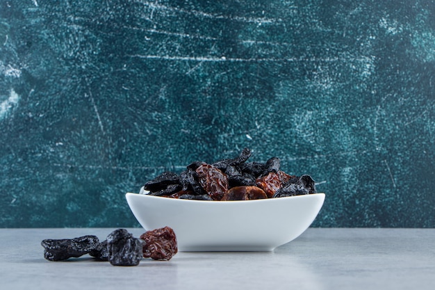 Free photo white bowl of tasty dried dates on stone background.