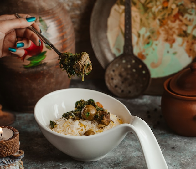 A white bowl of traditional govurma plov with dry fruits and chestnuts