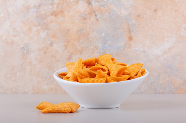 White bowl of triangle chips on marble background. High quality photo