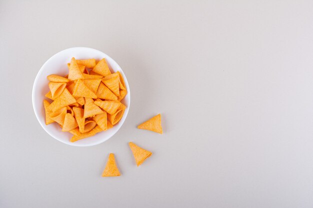 White bowl of triangle chips on marble background. High quality photo
