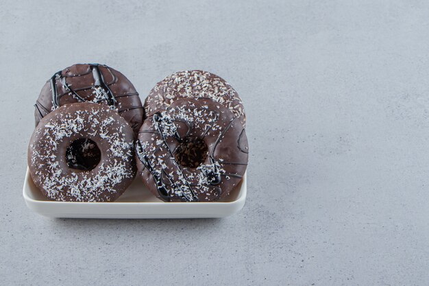 White bowl of two chocolate donuts on stone background. High quality photo