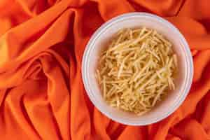 Free photo white bowl with potato straw on orange background