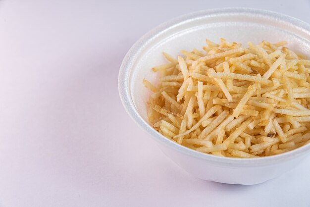 White bowl with potato straw on white background