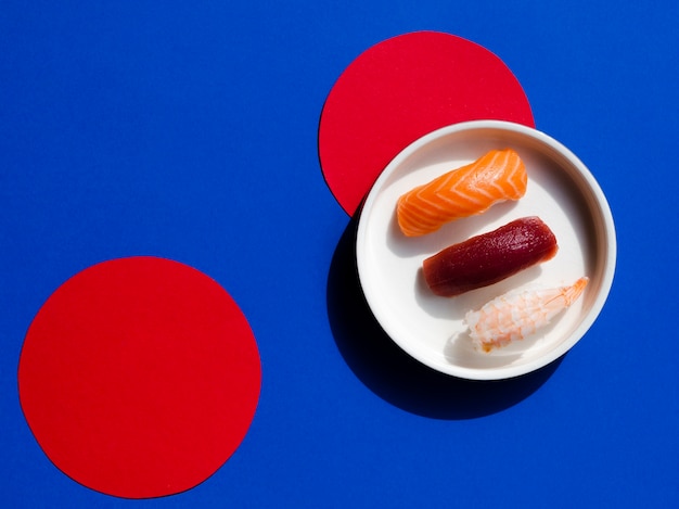White bowl with sushi on a blue and red background