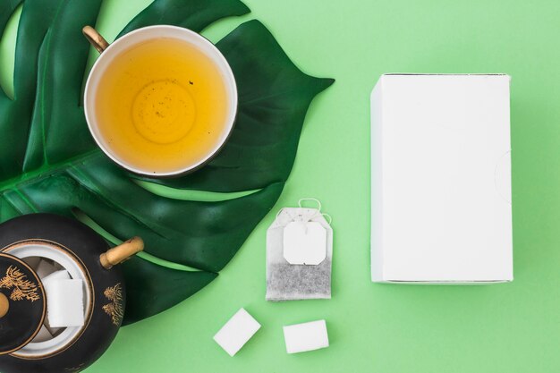 白い箱、緑茶の背景にハーブティー、砂糖立方体とティーバッグ