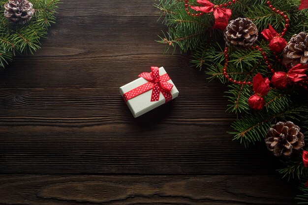 White box with a red bow on a wooden table with christmas ornament