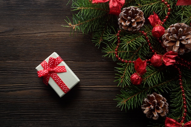 White box with a red bow on a wooden table with christmas ornament