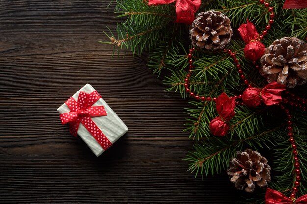 White box with a red bow on a wooden table with christmas ornament