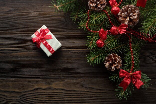 White box with a red bow on a wooden table with christmas ornament