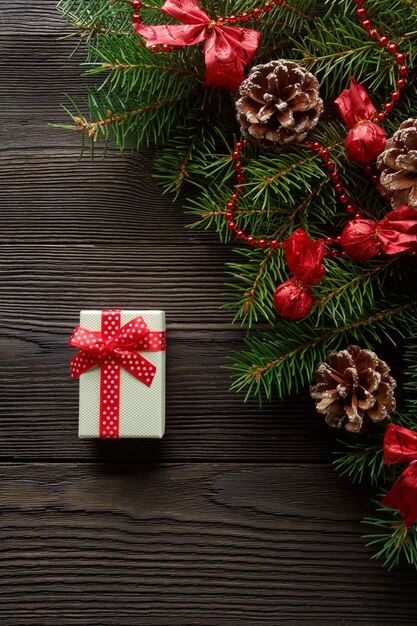 White box with a red bow on a wooden table with christmas ornament