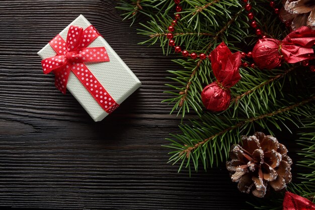 White box with a red bow on a wooden table with christmas ornament