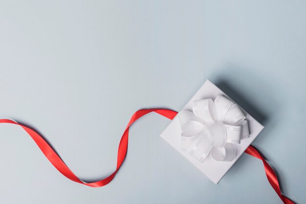 White box with red ribbon on gray background