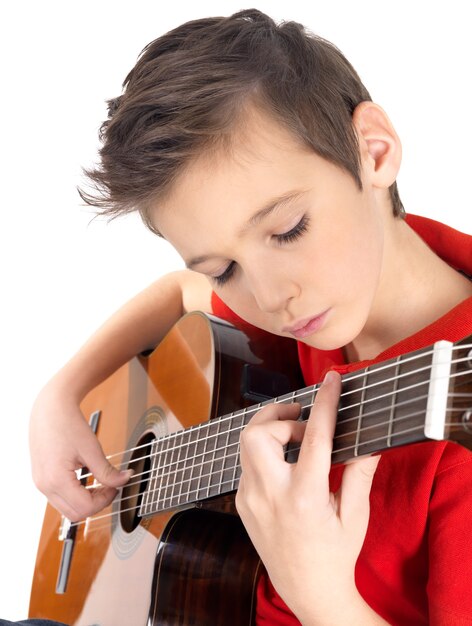 白人の少年は白で隔離のアコースティックギターで遊んでいます