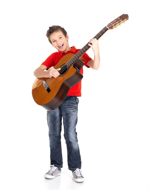 白人の少年は、白で隔離されたアコースティックギターで歌って演奏します