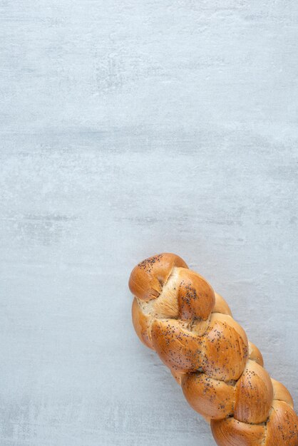 Белый плетеный хлеб на каменном столе.