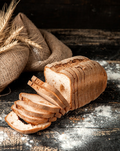 白パンは小麦粉と小麦のテーブルの上に白パンをスライス