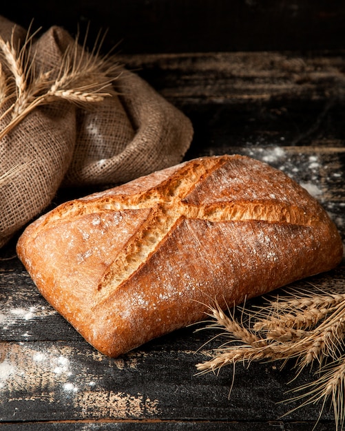 Pane bianco con farina di crosta croccante e grano sul tavolo