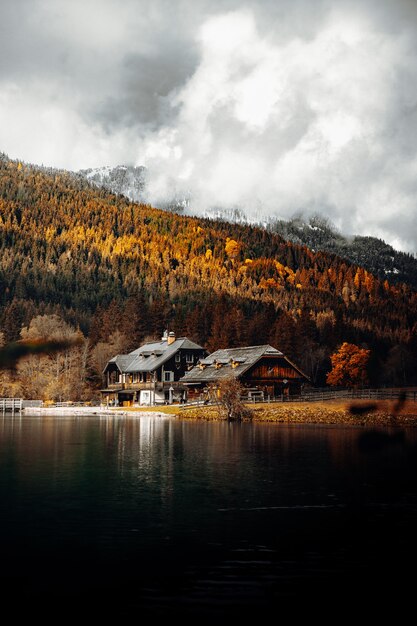 White and brown house near lake and green trees under white clouds and blue sky during