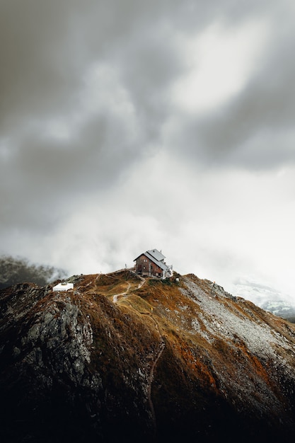 Foto gratuita casa bianca e marrone in cima alla montagna marrone sotto nuvole bianche