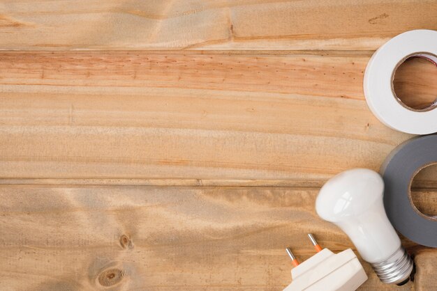 White bulb; insulating tape and button over wooden table