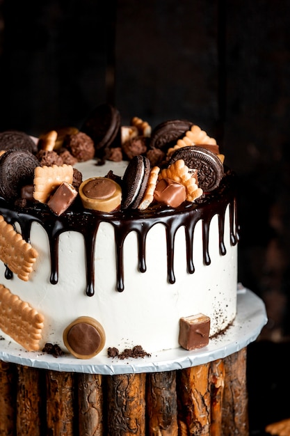 無料写真 チョコレートを注ぎ、オレオとトフィフィのクッキーで飾られた白いケーキ