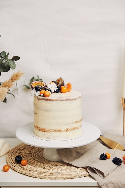 Белый торт с ягодами и маракуйей рядом с растением на белом фоне