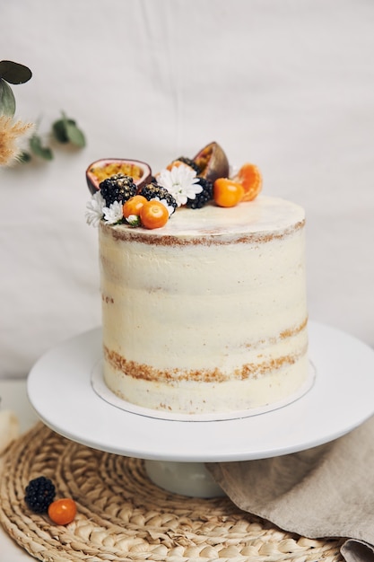 White cake with berries and passionfruits with plants