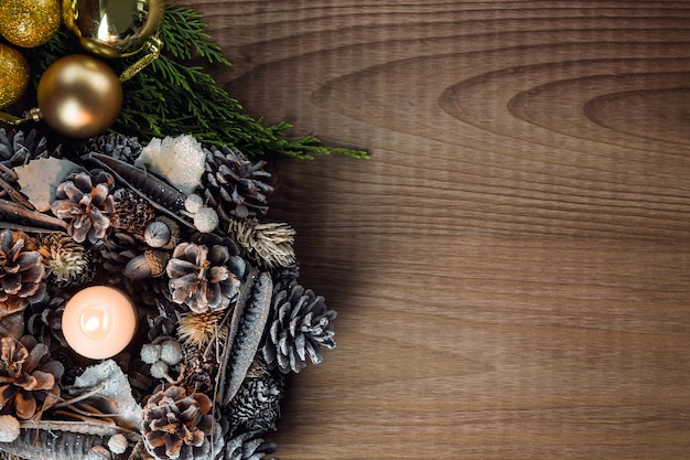 White candle lit with pine cone ornaments seen from above