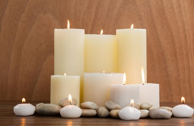 White candles and pebbles stone on wood