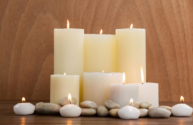 White candles and pebbles stone on wood