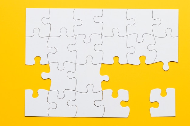 Free photo white cardboard jigsaw puzzles on yellow background