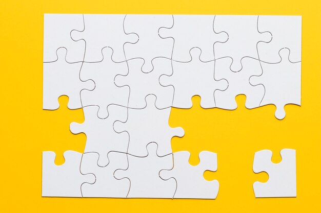 White cardboard jigsaw puzzles on yellow background