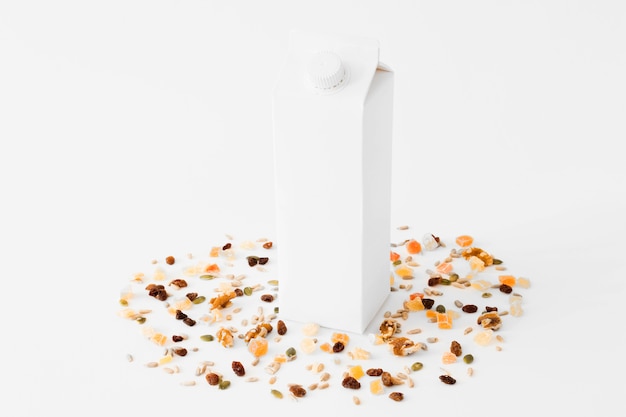 Белая картонная молочная упаковка между сухофруктами и орехами