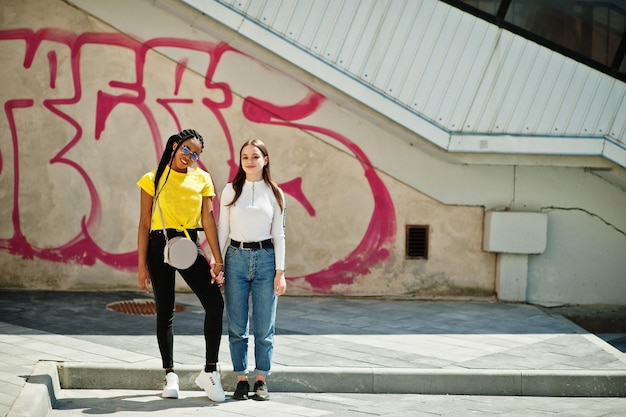 Free photo white caucasian girl and black african american together against graffiti wall world unity racial love understanding in tolerance and races diversity cooperation