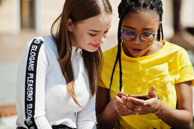 Foto gratuita la ragazza caucasica bianca e l'afroamericano nero guardano insieme il telefono cellulare la comprensione dell'amore razziale dell'unità mondiale nella tolleranza e nella cooperazione sulla diversità delle razze