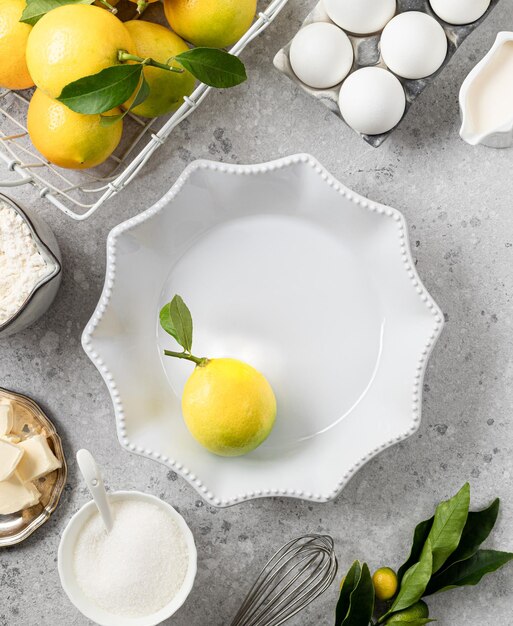 White ceramic cake pan with lemons Ingredients for making a lemon curd pie on a white stone table