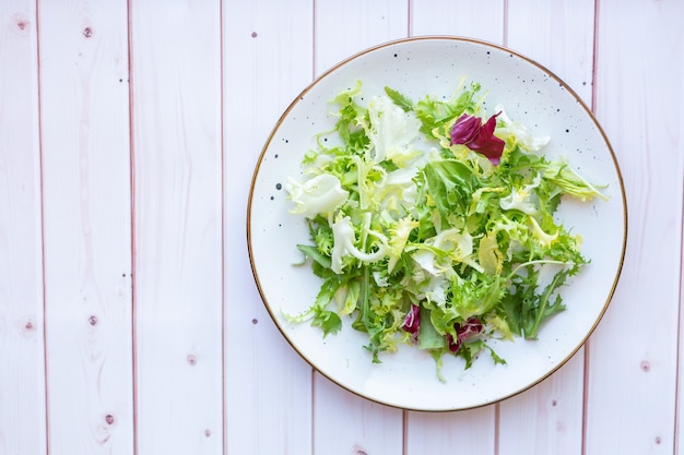 White ceramic plate with fresh salad on wooden surface