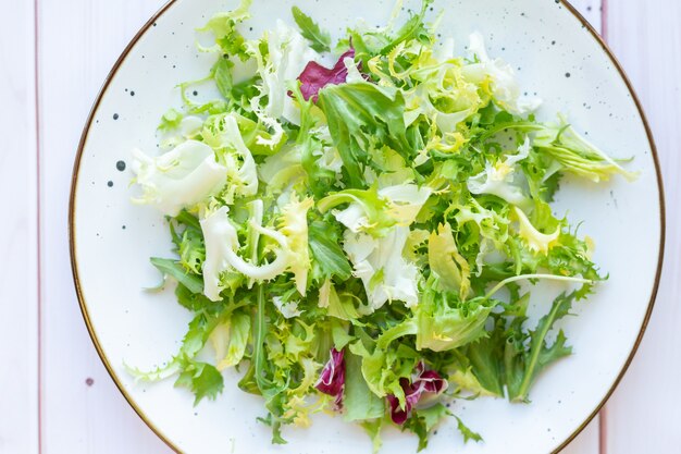 White ceramic plate with fresh salad on wooden surface