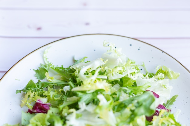 White ceramic plate with fresh salad on wooden surface