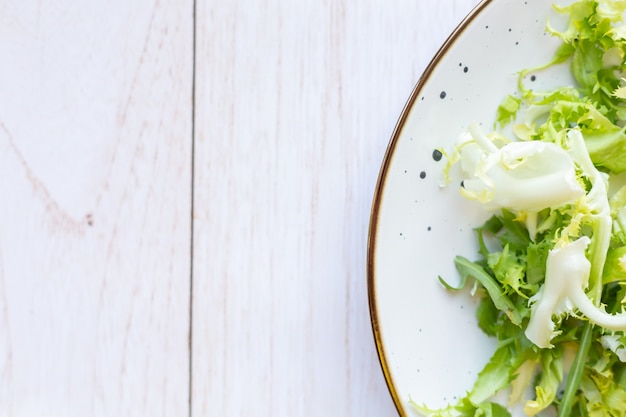 White ceramic plate with fresh salad on wooden surface