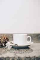 Free photo white ceramics cup and saucer on reflective marble table