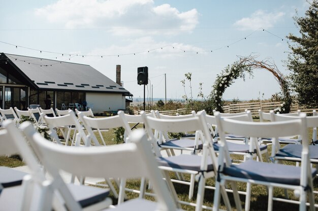 White chiavari chairs for guests, ceremonial wedding arch on the decorated for the wedding ceremony