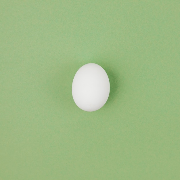 White chicken egg on green table