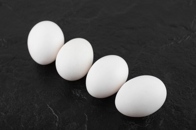 White chicken eggs on a black table . 