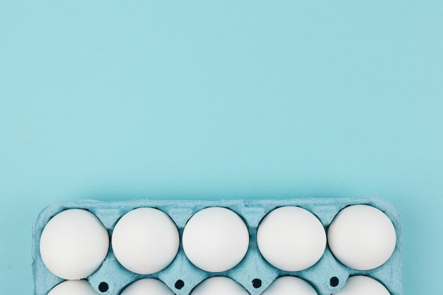 Free photo white chicken eggs in rack on blue table