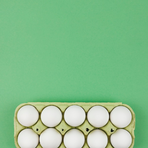 White chicken eggs in rack on green table