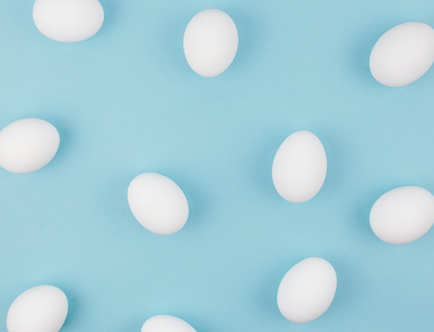 White chicken eggs scattered on blue table