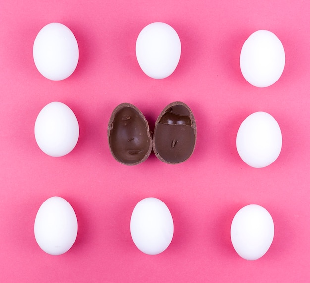 White chicken eggs with open chocolate egg on table