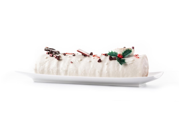 白い背景に分離されたクリスマスの飾りとホワイト チョコレート ユール ログ ケーキ