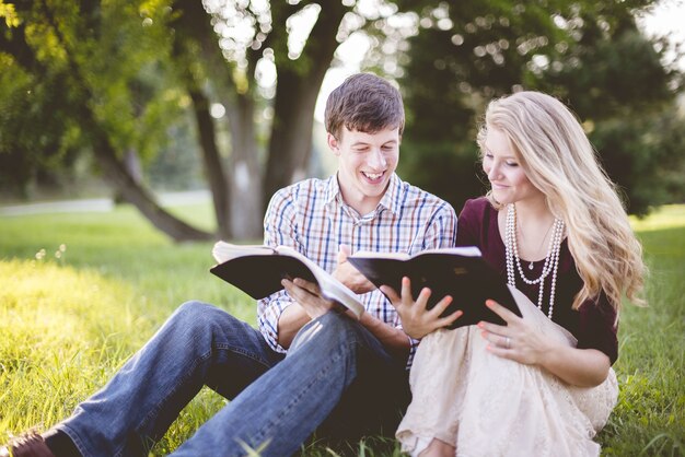 White Christian couple enjoying reading the Bible in the middle of a field